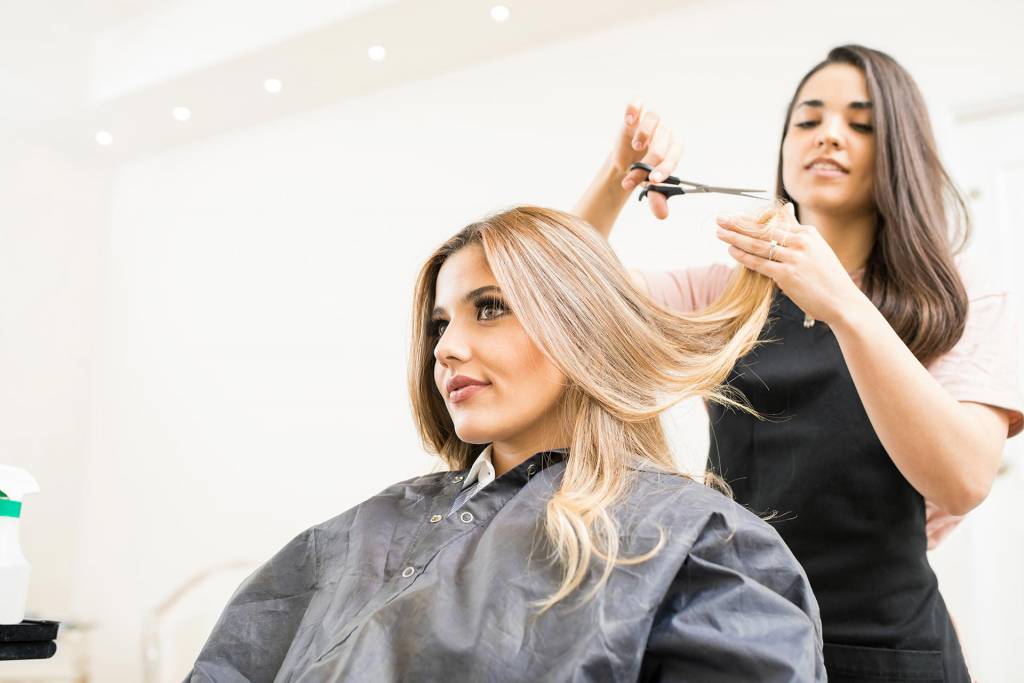 female-hair-stylist-cutting-female-blonde-hair-client-sitting-in-chair-cutting-tips